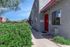 Inviting apartment exterior showcasing a vibrant red door and lush greenery in a serene setting.