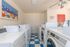 Bright and airy laundry room with modern washing machines, vibrant artwork, and checkerboard flooring, perfect for residents.