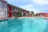 Inviting apartment complex with a sparkling pool, vibrant red doors, and relaxing outdoor seating, perfect for leisure.