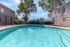 Inviting turquoise pool surrounded by lush greenery and modern apartment buildings, perfect for relaxation and leisure.