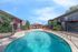 Inviting apartment complex featuring a sparkling swimming pool, vibrant red seating, and well-maintained landscaping under a clear blue sky.