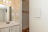 Bright bathroom area with a modern vanity, elegant lighting, and a spacious closet for ample storage.