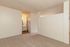 Bright and spacious apartment room featuring plush carpet flooring, a modern vanity area with warm lighting, and ample closet space for a cozy and functional living environment.