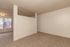Spacious living room with plush carpet, modern partition, and large window offering ample natural light.