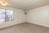 Bright and inviting corner room with plush carpeting, large window for natural light, and modern wall AC unit.