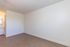 Bright room with sleek hardwood flooring, minimalist design, and a vanity leading to a bathroom.