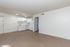 Inviting open-plan living space with a modern kitchen, featuring sleek white cabinets and bright recessed lighting on stylish flooring.