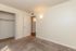 Bright and inviting empty room with a cozy carpet, ample closet space, and soft lighting, perfect for personalization.