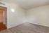 Bright, freshly carpeted room with soft lighting and attached bathroom, perfect for a cozy personal retreat.