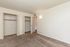 Bright and spacious bedroom with plush carpet, two open closets, and modern wall lighting.