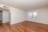 Inviting apartment interior with warm wood flooring, neutral walls, and abundant natural light through a large window.