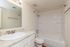 Bright and modern bathroom featuring a marble countertop, sleek fixtures, and a pristine bathtub.