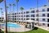 Chic modern apartment complex with pristine swimming pool, tall palm trees, and sun loungers, offering a relaxing lifestyle.