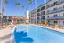 Luxurious apartment complex featuring a vibrant swimming pool and stylish lounge area under sunny skies.