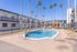 Inviting apartment complex courtyard featuring a sparkling pool, surrounded by palm trees and sun loungers, perfect for relaxation.