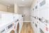 Modern apartment laundry room featuring sleek white washers and dryers with wooden flooring and bright lighting.