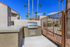 Inviting outdoor space featuring a modern built-in grill, surrounded by lush palm trees and elegant architecture under a clear blue sky.