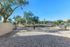 Inviting outdoor area with a gated entrance surrounded by lush trees and a clear blue sky.
