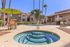 Inviting apartment complex with sunlit courtyard, featuring a refreshing pool and jacuzzi, surrounded by palm trees and stylish outdoor seating for a perfect relaxation haven.