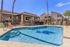 Inviting outdoor pool area with sun loungers and charming palm trees, perfect for relaxation in a stylish apartment community.