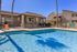 Inviting outdoor pool area with pristine blue water, adjacent sun lounge, and modern building with shaded seating, perfect for relaxation.