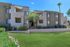 Charming apartment complex with sunny balconies, lush landscaping, and vibrant green lawns inviting a sense of calm and relaxation.