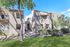 Charming apartment complex exterior with inviting balconies, vibrant landscaping, and scenic views under a clear blue sky.
