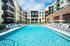 Luxurious apartment complex with a pristine swimming pool, surrounded by stylish lounge chairs, offering a perfect blend of modern architecture and resort-like relaxation.