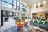 Luxurious apartment lounge with high ceilings, vibrant seating, and a scenic poolside view through expansive windows.