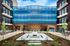 Vibrant urban courtyard with modern balconies, lush landscaping, and eye-catching blue wave mural.