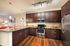 Modern kitchen with sleek dark wood cabinetry, stainless steel appliances, and elegant pendant lighting over a spacious granite countertop.