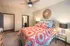 Cozy and vibrant bedroom with a stylish patterned bedspread, plush pillows, and elegant lighting, perfect for relaxing.