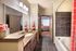 Inviting bathroom with elegant granite countertops, modern fixtures, and a stylish bathtub, leading into a cozy bedroom with vibrant decor.