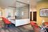 Elegant lobby with contemporary design featuring bright red chairs, a modern glass partition, and a stylish glass dining table.