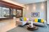 Modern living room with sleek gray sectional, vibrant yellow and blue pillows, and chic wooden coffee table in a stylish, open-concept layout.