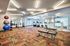 Modern fitness center with vibrant patterned carpet featuring gym equipment, exercise balls, and windows for natural light.