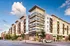 Modern urban apartment complex showcasing contemporary architecture with ample balconies and vibrant street-level shops.