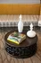Elegant coffee table with artistic circular design, featuring decorative white vases and a stack of stylish books, set against a luxurious yellow and gray sofa.