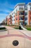 Modern apartment complex with vibrant brick and white exterior, featuring balconies and lush landscaping in the scenic Nickel Plate District.
