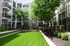 Charming apartment courtyard with lush greenery, comfortable seating areas, and modern balconies, perfect for relaxation.