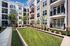Modern apartment complex showcasing elegant balconies, lush green courtyard, and inviting outdoor seating area.