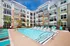 Luxury apartment complex with a sparkling outdoor pool, surrounded by vibrant sun loungers and modern architecture, perfect for relaxation and leisure.