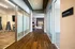 Elegant hallway with polished wood floors leading to a modern yoga studio and a fitness area with sleek equipment.