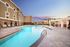 Luxurious apartment complex with a stunning outdoor pool area, surrounded by stylish seating and modern architecture, perfect for relaxation and entertainment.
