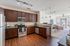 Bright modern kitchen with sleek cabinetry, stainless steel appliances, and open layout leading to a sunlit living room with stylish decor.