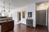 Modern apartment interior showcasing a sleek kitchen with granite countertops, stylish pendant lighting, and rich wooden floors.
