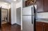 Contemporary kitchen with stainless steel appliances, elegant dark wood cabinetry, and convenient adjacent laundry room.