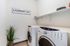 Modern laundry room featuring sleek washer and dryer, chic wall art, and stylish shelving for a functional and elegant space.