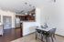 Modern kitchen and dining area with sleek pendant lighting, stainless steel appliances, and elegant wooden cabinetry, offering a sophisticated ambiance.