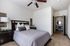Serene bedroom with plush bedding, elegant nightstand, and inviting natural light leading to a stylish office space.